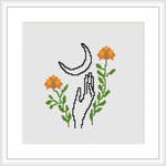 The image presents a cross stitch pattern featuring illustrated hands reaching towards a crescent moon, surrounded by leaves and blooming flowers.