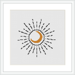 The image shows a framed cross stitch pattern of a stylized crescent moon with lines radiating outward to represent its glow, all stitched on a white canvas.