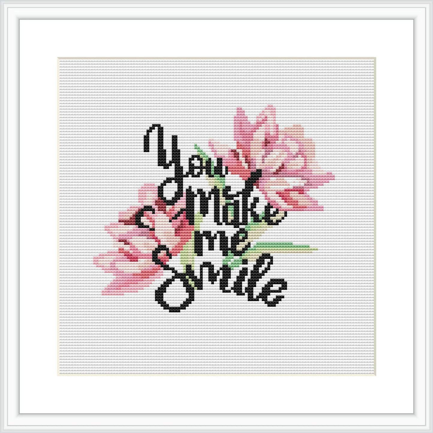 The image shows a framed cross stitch design featuring pink flowers and green leaves, with the phrase 'You make me smile' incorporated into the pattern, all against a white background.