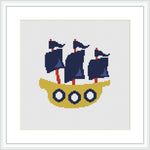 The image depicts a stylized cross stitch pattern of a yellow boat with three blue sails on a white background. Portholes and a flat-bottomed boat shape are prominently featured.