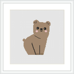 The image shows a framed cross stitch pattern of a cartoon-like bear with a simple color palette, mainly comprising shades of brown, positioned in the center against a plain white background.