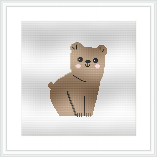 The image shows a framed cross stitch pattern of a cartoon-like bear with a simple color palette, mainly comprising shades of brown, positioned in the center against a plain white background.