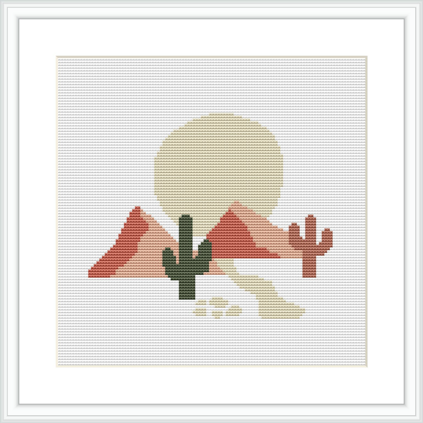 The image depicts a cross stitch pattern featuring a desert scene with two cacti in the forefront, and mountains with a large setting sun in the background, all framed within a white border.