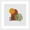 The image shows a framed cross stitch pattern with a centered round element representing the sun in a golden yellow, semi-circular shapes in rust orange below the sun suggesting a landscape, and a green monstera leaf with brown accents to the bottom right, against a plain white background.