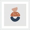 The image displays a cross stitch pattern framed in a white square frame against a white background. The pattern itself consists of three abstract shapes stacked to resemble a simplistic house or dwelling, with the topmost shape colored salmon pink, followed by a coral shade with white polka dots, and a navy blue base that suggests stability.