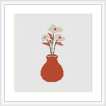 The image depicts a cross stitch pattern featuring a crimson red vase with a handful of white blooms and sprigs of green leaves, all set against a plain white background within a square frame.