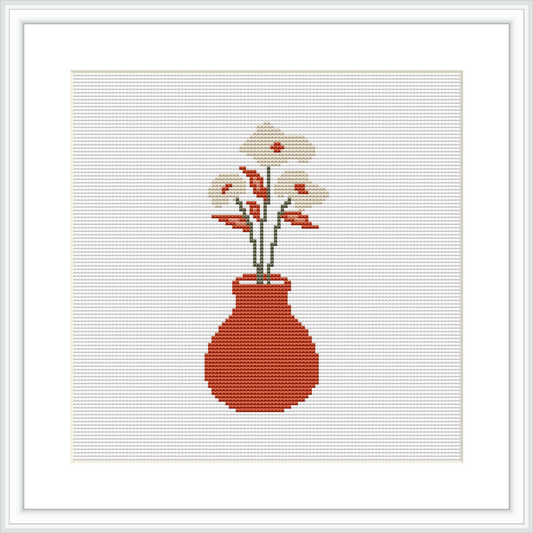 The image depicts a cross stitch pattern featuring a crimson red vase with a handful of white blooms and sprigs of green leaves, all set against a plain white background within a square frame.