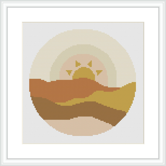 The cross stitch pattern depicts a stylized sunset with a gradient of colors representing hills or dunes under a large, circular sun with rays emanating from it, all framed within a square border.