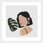 The image depicts a side profile of a woman with black hair, her face turned slightly downwards, and a large green tropical leaf partially obscuring her face. She wears a strapless top and an earring. The design is framed against a white background.