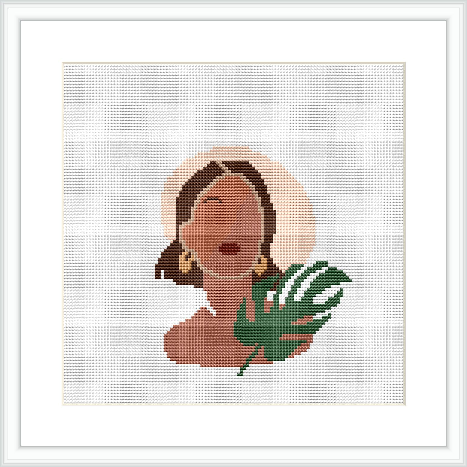 The image shows a framed cross stitch pattern. The pattern depicts a woman's profile with closed eyes and a serene expression. She appears to be wearing a large, round earring and there is a stylized tropical leaf beside her. The background is plain, allowing the figure to stand out.