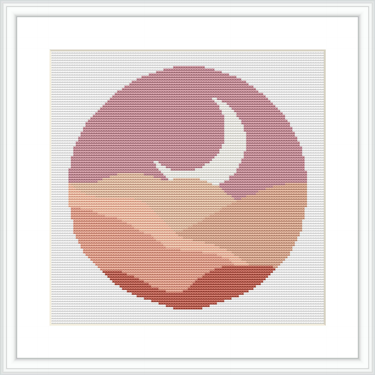 The image depicts a cross stitch pattern featuring a circular abstract design. The design showcases a crescent moon amid a backdrop resembling a dreamy sky or cloudscape, all contained within a round frame and presented against a white background.