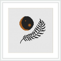 The image displays a framed cross stitch pattern featuring a crescent moon in shades of orange and brown, with small stars, and a black fern leaf below it on a white background.
