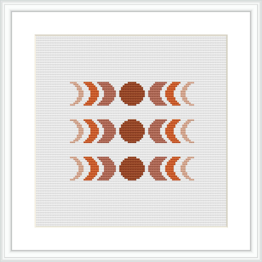 The image shows an abstract cross-stitch pattern comprised of circular and crescent shapes in a symmetrical arrangement. The design uses earthy brown and beige tones, centralized on a squared canvas, framed by a simple white border.