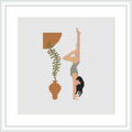 The image presents a cross stitch pattern showing a side view of a woman in a yoga headstand pose. The woman's body is portrayed in sandy brown and peach colors, with a black skirt or shorts. She is positioned on a white background with a simple representation of an olive green potted plant above her.