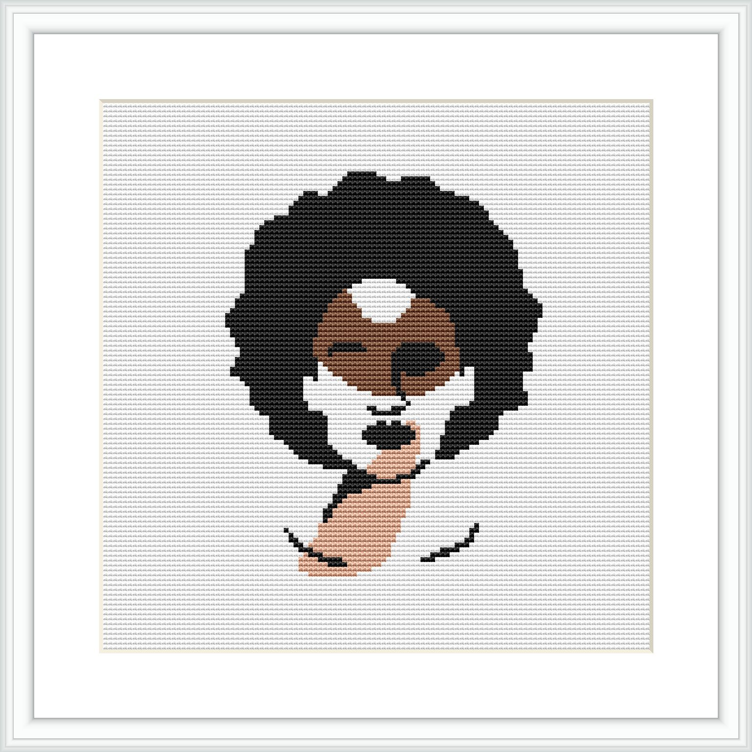 The image displays a framed cross stitch pattern hung on a wall. The design features an abstract illustration of a woman's face with geometric shapes and a limited color palette.