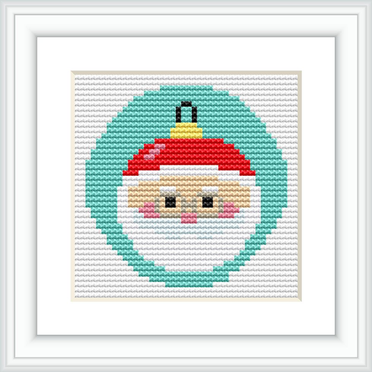 A framed cross stitch pattern of Santa Claus's face depicted within a Christmas ornament. The background is segmented by color, with a dominant green color encircling Santa's face, followed by a white border and a red top suggestive of an ornament cap.