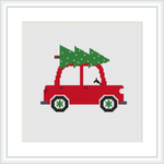 The image depicts a cross stitch pattern framed in white, showcasing a red car with green wheels and windows, carrying a green Christmas tree on the roof against a plain white background.