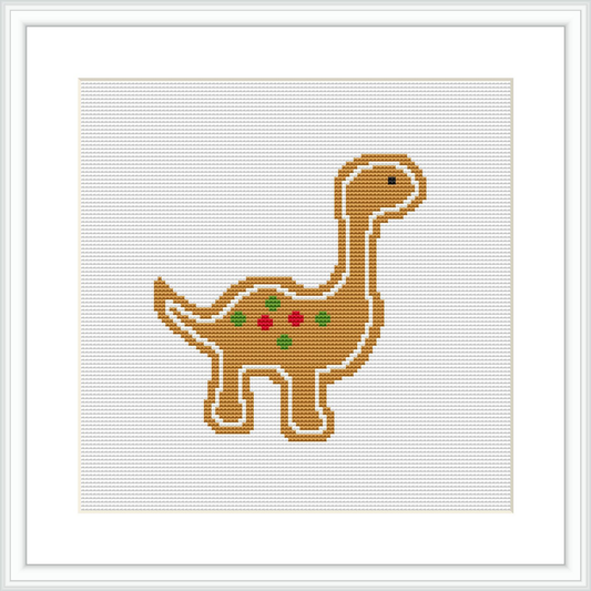 The image depicts a brown dinosaur with a long neck standing upright. It is decorated with red and green dots along its back, resembling Christmas ornaments. The dinosaur is framed within a white border on a beige background, suggesting the grid of a cross stitch fabric.