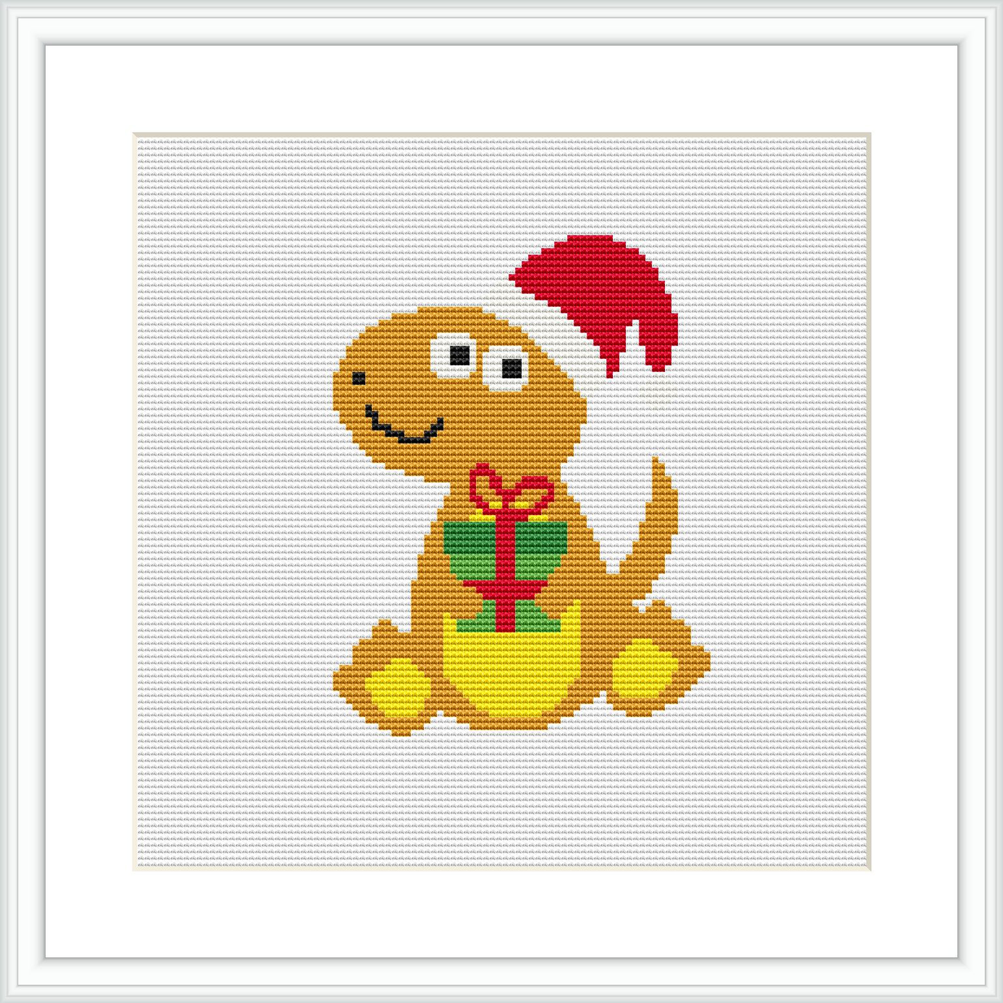 The image displays a completed cross stitch pattern framed in white. It depicts a cartoonish dinosaur, sitting with a smile, wearing a red Christmas hat and holding a green gift box with a red ribbon. The background is plain white.