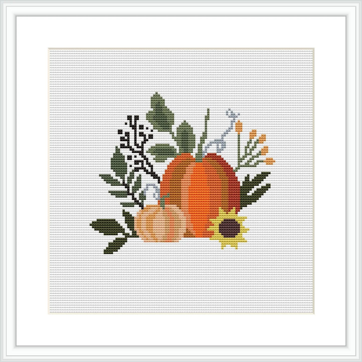 The image depicts a cross stitch pattern with a central large pumpkin, a smaller pumpkin to its left, a sunflower below, and assorted leaves and berries surrounding them on a white background, encased in a simple frame.