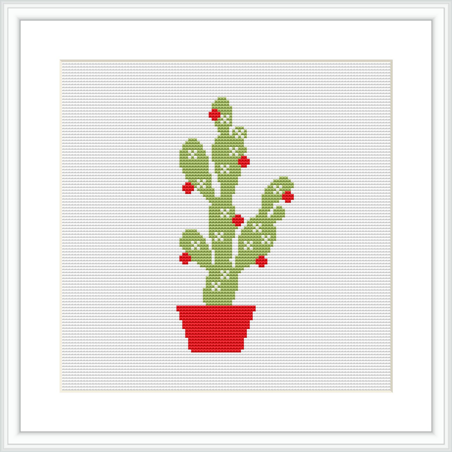 The image features a cross stitch pattern of a green cactus with multiple arms, each dotted with red Christmas ornaments. The cactus sits in a bright red pot and is displayed against a plain white fabric background within a simple, white square frame.