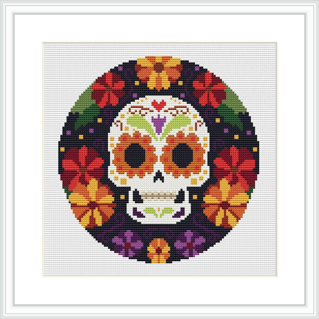 The image depicts a circular cross stitch pattern of a stylized skull surrounded by a border of colorful flowers. It's meant to represent a Mexican-themed Day of the Dead motif.