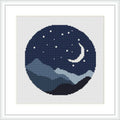 The cross stitch pattern depicts a circular motif featuring a stylized night scene with a crescent moon in the sky and a layered mountain landscape beneath, all encompassed within a round frame.