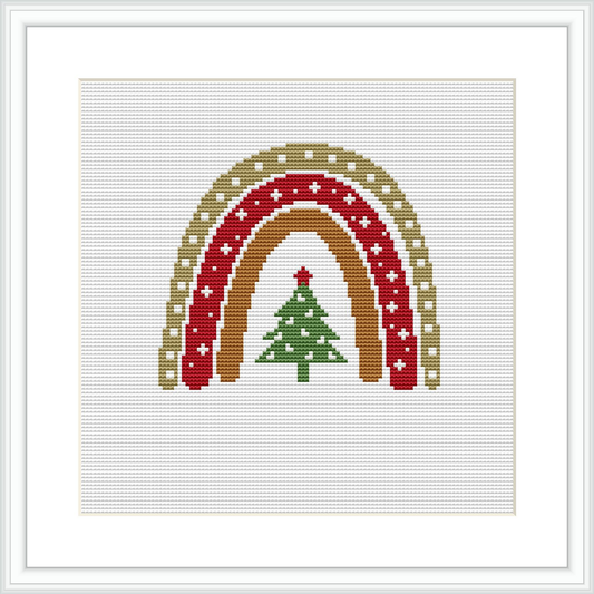 The image depicts a framed cross stitch pattern with a Christmas theme. It presents three rainbow arcs in colors of red, gold, and beige. Below the arcs, a green Christmas tree is centered, adorned with simple decorations and topped with a golden star. The background is white, and the design is square-shaped within a frame.