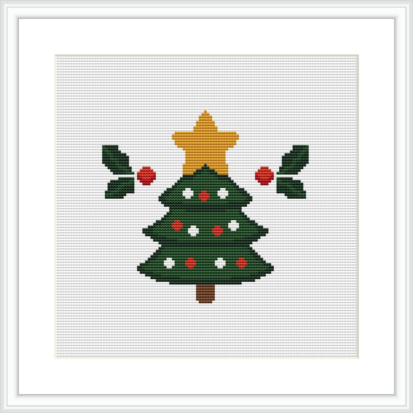 The image showcases a completed cross stitch pattern framed against a white background. The pattern features a traditional Christmas tree, decorated with red ornaments and a gold star on top, flanked by two branches of holly with red berries.