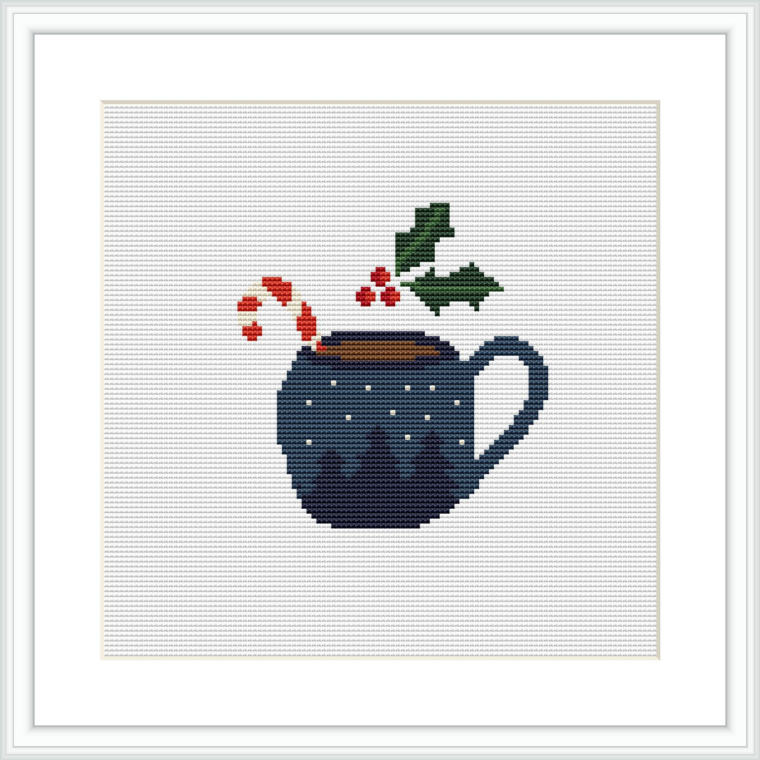 The image shows a cross stitch pattern design of a dark blue chocolate pot with small white speckles, suggesting a snowy appearance. Above the pot, there are elements of holly and berries. The pattern is centered within a white canvas and framed in a simple picture frame.