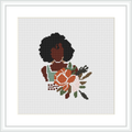 The image depicts a cross stitch pattern of a stylized woman with dark curly hair, wearing an orange and brown dress with a floral pattern. She is holding a bouquet of flowers and leaves, centered against a white background within a square frame.