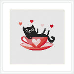 The image portrays a black cat lying comfortably inside a red teacup that has a heart design. There are small hearts floating around the cat. The background is plain white and the design is contained within a square frame.