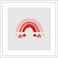 The image shows a cross stitch pattern of a stylized rainbow with alternating red and pink shades. Below the rainbow, there are several heart shapes in similar tones, all framed within a square white border on a white background.