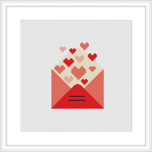 The image features a cross stitch pattern depicting an envelope in shades of red, with a variety of hearts in red and pink tones appearing to float out of it. The envelope is centered on a white background, and it is framed with a simple white border.