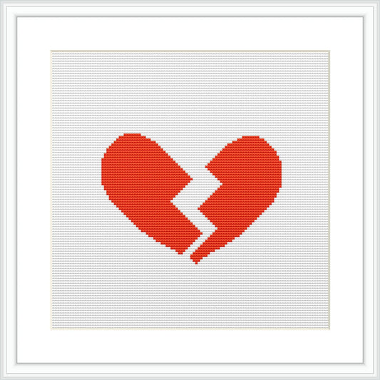 The image showcases a cross stitch pattern of a broken heart, centered on a white canvas, framed in a minimalist style with a simple black frame.