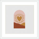 A cross stitch pattern featuring a stylized heart in the center with rays emanating from it, set against a background with a terracotta-colored bottom half and a peach-colored top half, reminiscent of a sunrise.