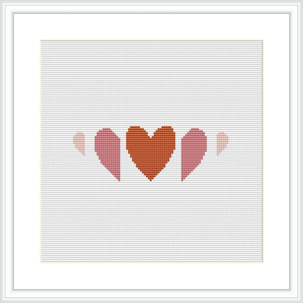 The image shows a cross stitch pattern with three heart shapes in a row, each decreasing in size from left to right. The hearts are filled with different shades of terra cotta and pink, creating a gradient effect. The pattern is displayed within a simulated white frame against a white background.
