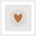 A cross stitch pattern displaying a centered brown heart with radiating lines and dots creating a sunburst effect, displayed on an ivory or white background within a frame.