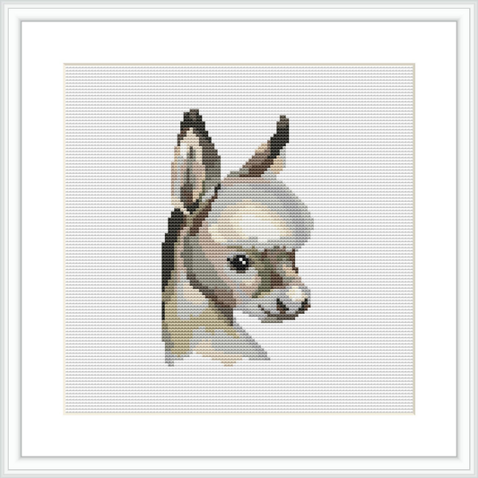 The image showcases a half body portrait of a donkey facing towards the viewer. The depiction is stylized in a pixelated manner consistent with a cross stitch pattern. The background is plain white, emphasizing the subject.