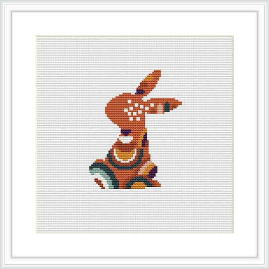 The image shows a stylized bunny in profile, stitched during Easter with a pattern predominantly featuring purple, orange, olive green, brown, and cyan colors. The bunny is enclosed in a square frame, signifying that it is a pattern design ready for cross stitching.