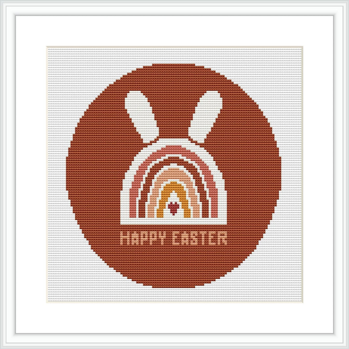 The image displays a framed cross stitch pattern showing a stylized brown bunny above a rainbow arc with the phrase 'HAPPY EASTER' at the bottom, all contained within a circular border.