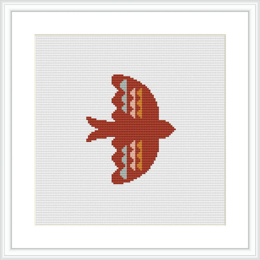 The image displays a cross stitch pattern of a bird silhouette in red, coral, and peach tones against a white background, framed in a simple white frame, suggesting a minimalist and symmetrical design.