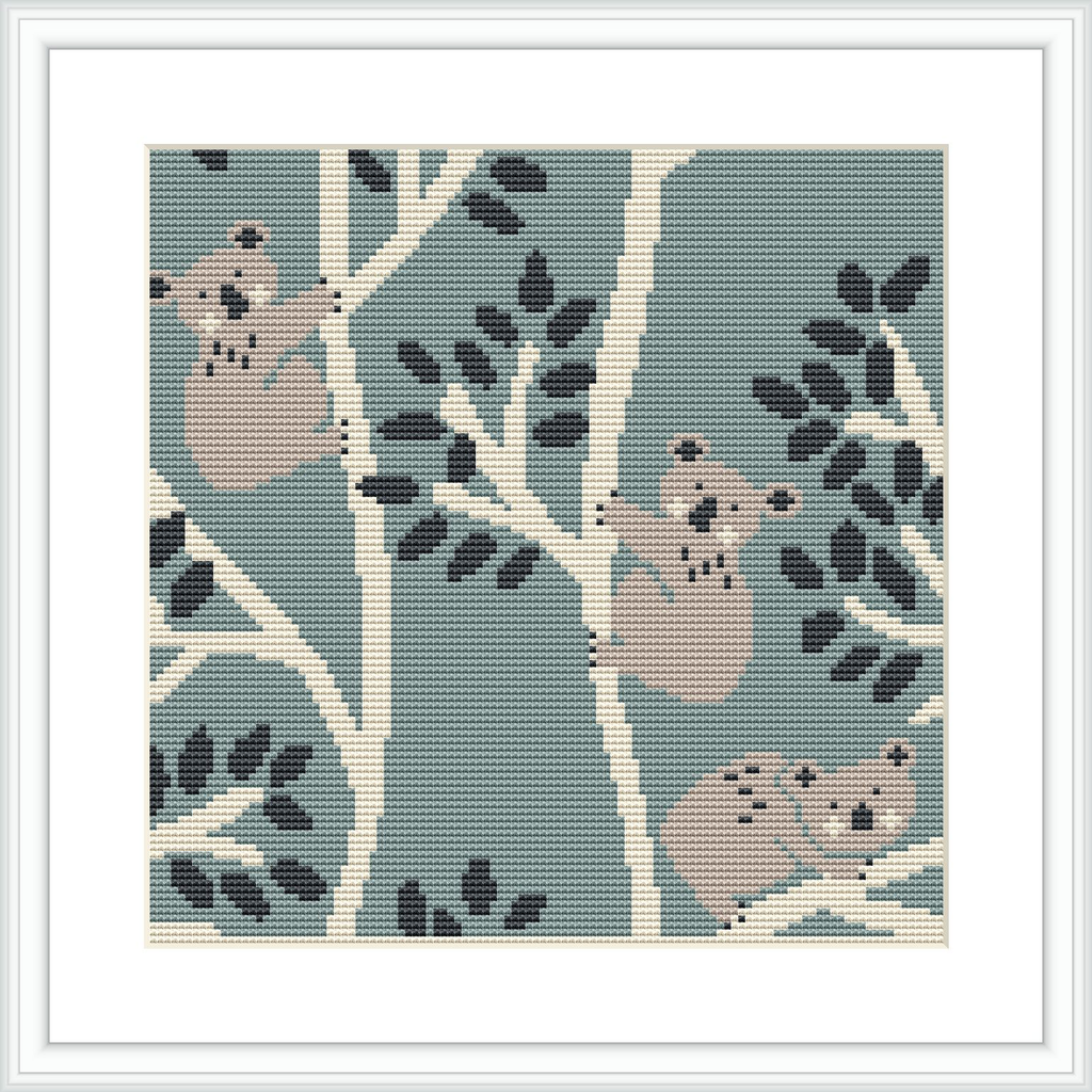 The image features a cross-stitch pattern representing four koalas nestled among patterned eucalyptus branches on a sage green background. The design is bordered by a clean, white frame.