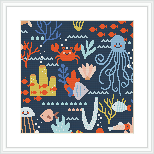The image displays a framed cross stitch pattern featuring an ocean theme with various sea creatures and plants, such as an octopus, jellyfish, corals, and seaweed against a dark background.