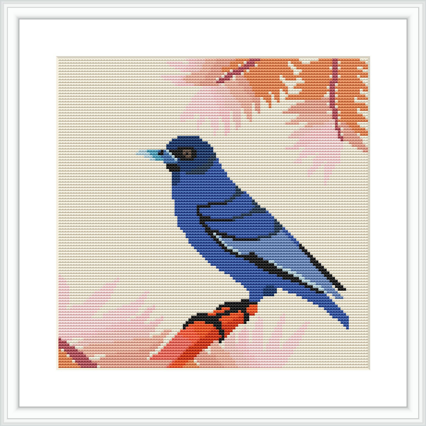 The image shows a framed cross stitch design featuring a blue bird perched on a branch against a cream background with shaded peach fern leaves.