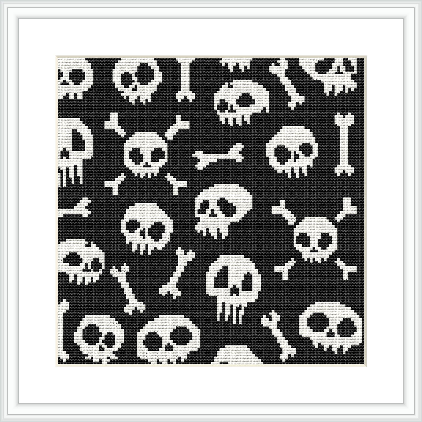 A framed cross stitch pattern depicting various skulls and bones in a monochromatic black-and-white color scheme against a dark background. The design is evenly spaced and features multiple repetitions of the skull and bones motif.