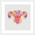 The image features a colorful cross stitch pattern depicting a stylized floral design that resembles a womb, with a mix of flowers and leaves. The design is framed and displayed on a white background.