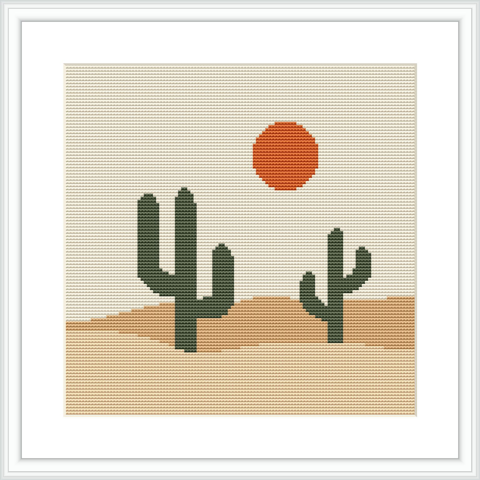 The image depicts a stylized cross stitch pattern of a desert scene with two green cacti in the foreground, a terracotta ground, and a large orange sun against an azure sky background, all contained within a simple frame.