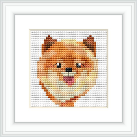 The image shows a framed cross stitch pattern of a Pomeranian dog's face. The design is simple, using a small range of colors to replicate the furry features of the breed.