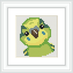 The image displays a framed cross stitch pattern depicting a green and yellow parakeet with a white background. The pattern is stitched onto fabric and is showcased within a white square frame.